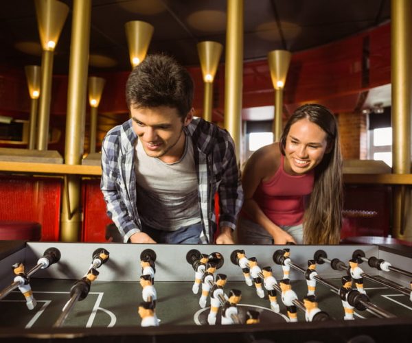 Smiling friends playing table football together in a pub
